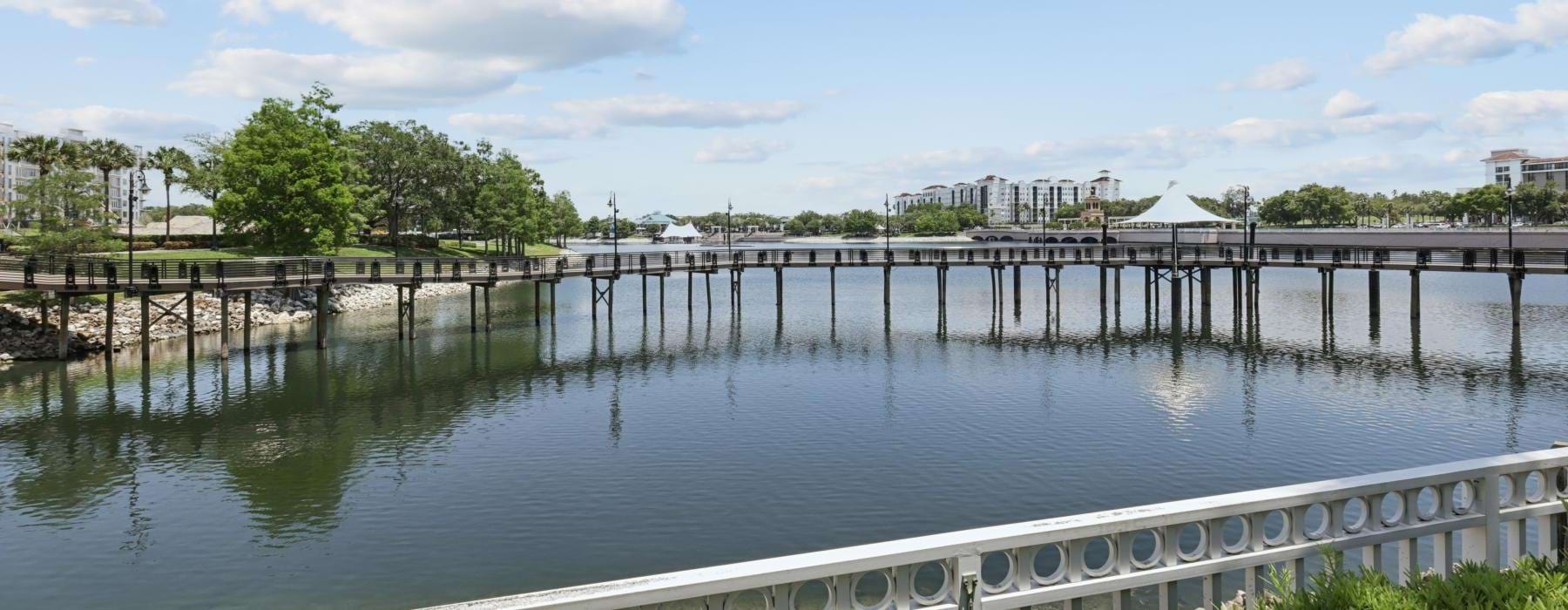 a body of water with a bridge and trees in the background